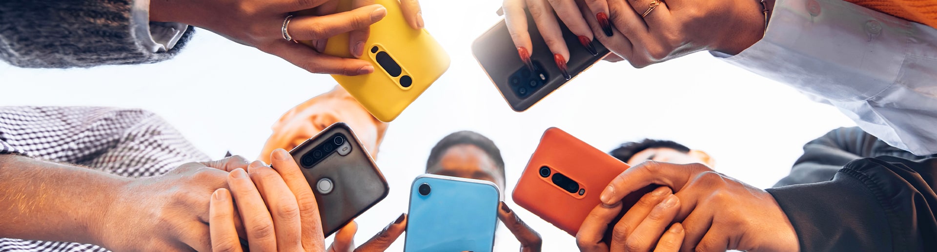 A group of teens in a huddle watch a video on their own devices